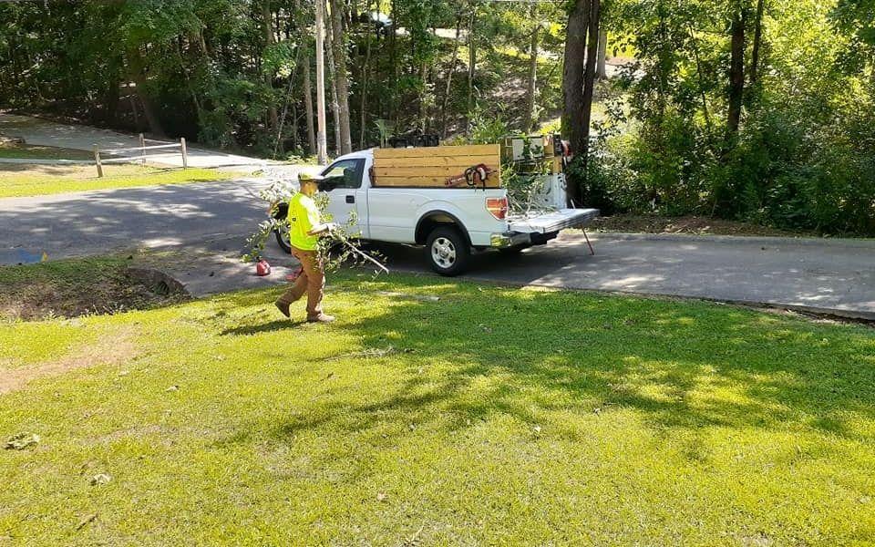 A Parsonic Services employee cleaning up fallen limbs during a landscape maintenance service.