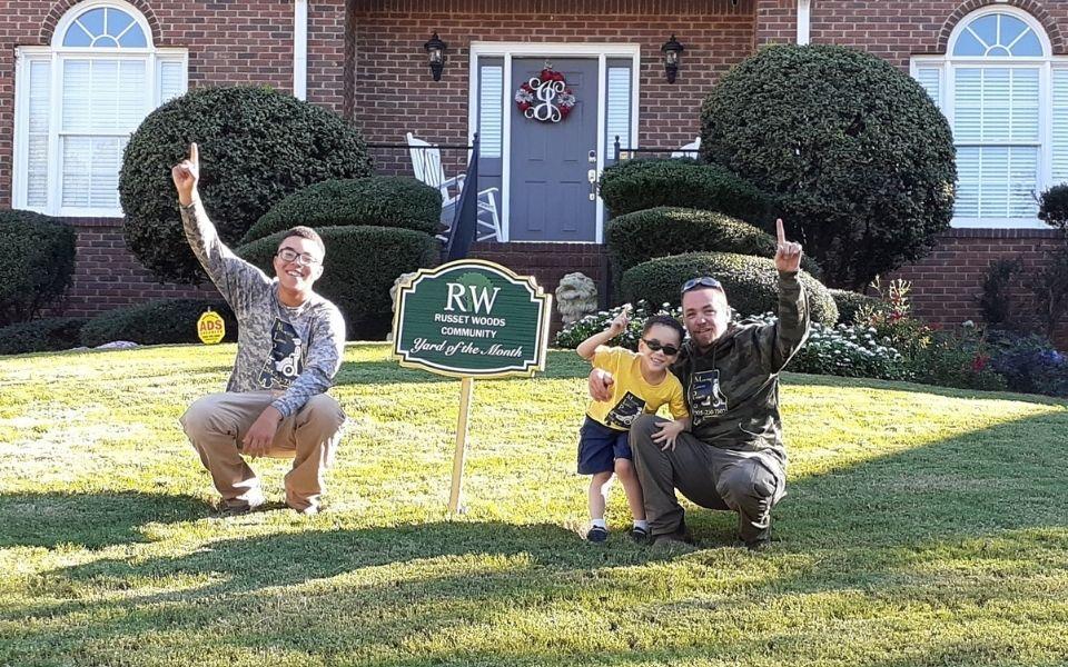 The owner of Parsonic Services posing on a client's lawn with other members of his team.